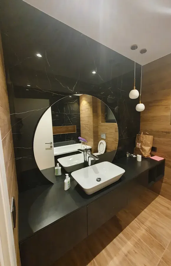 Baie cu marmură neagră, oglindă rotundă și blat suspendat — mobilier de baie la comandă Fine Cut Furniture