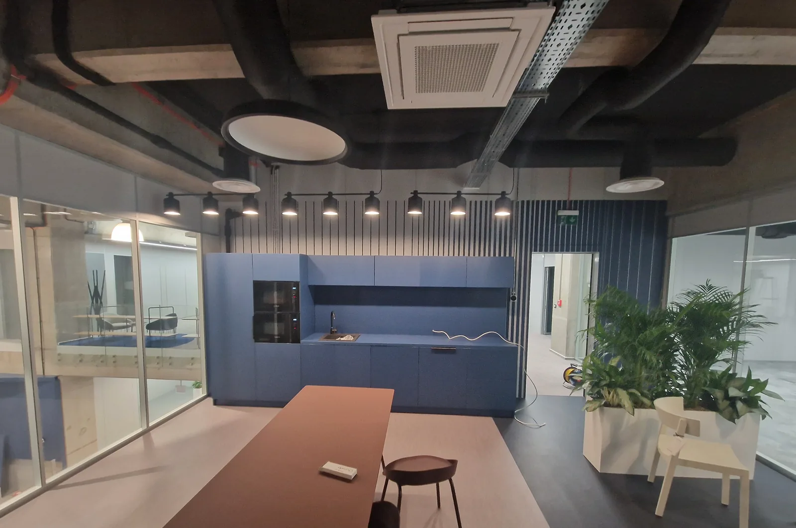 Zonă de socializare într-un birou, cu bucătărie albastră și masă lungă — mobilier comercial la comandă Fine Cut Furniture, Giarmata-Vii