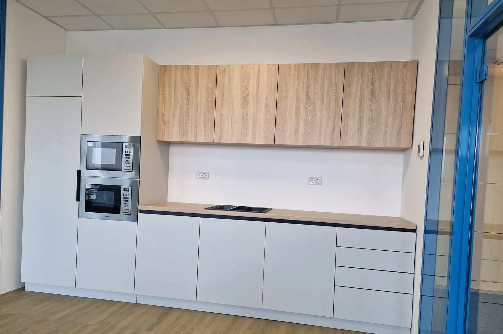 Chicinetă de birou albă cu corpuri suspendate în decor lemn — mobilier comercial la comandă Fine Cut Furniture, Timișoara